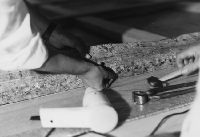 Manos clavando el lienzo de Guernica al bastidor con tachuelas en el Casón del Buen Retiro