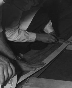 Manos colocando la cinta para unir el lienzo de Guernica al bastidor en el Casón del Buen Retiro