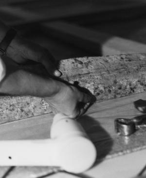 Manos clavando el lienzo de Guernica al bastidor con tachuelas en el Casón del Buen Retiro